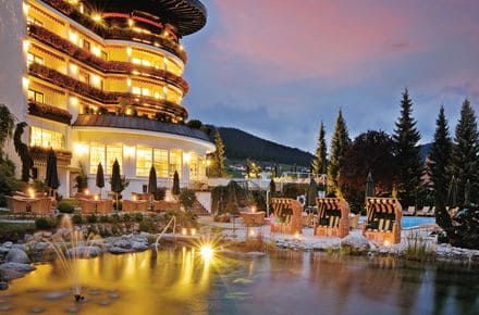 Außenansicht des beleuchteten Luxushotel Schwarzwald in der Abenddämmerung